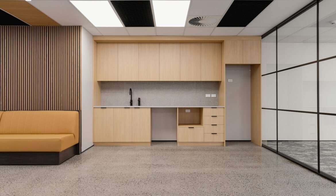 Modern office kitchenette with wooden cabinets and sofa