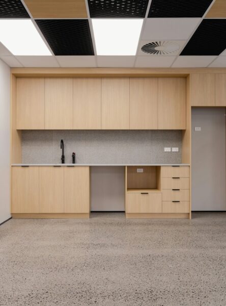 Modern office kitchenette with wooden cabinets and sofa