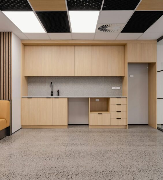 Modern office kitchenette with wooden cabinets and sofa