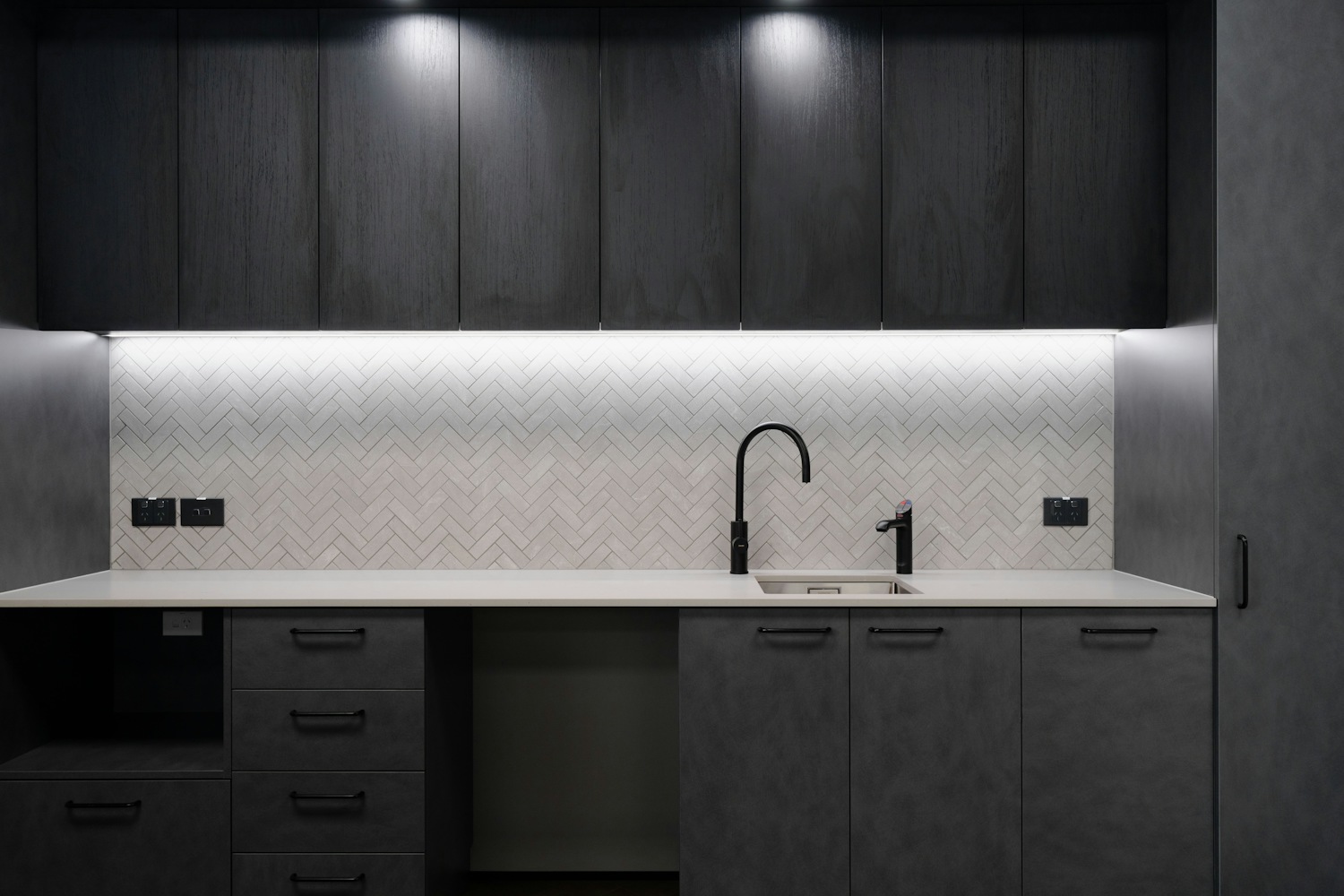 Modern dark kitchen with herringbone tile splashback