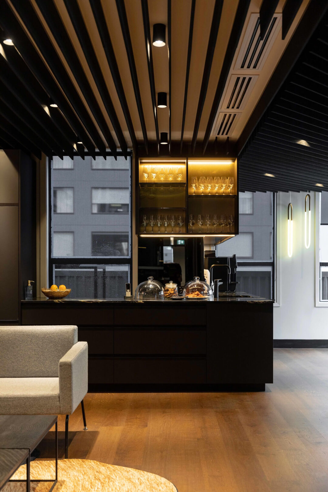 Modern office kitchen with dark cabinetry and lighting.