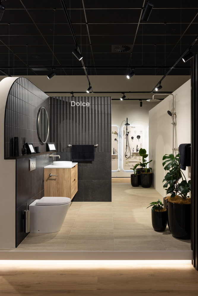 Modern bathroom showroom with black tiles and wood vanity