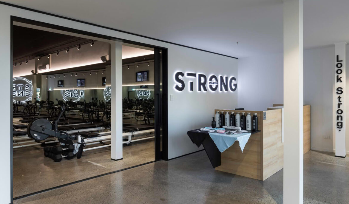 Modern Pilates studio entrance with equipment and signage.